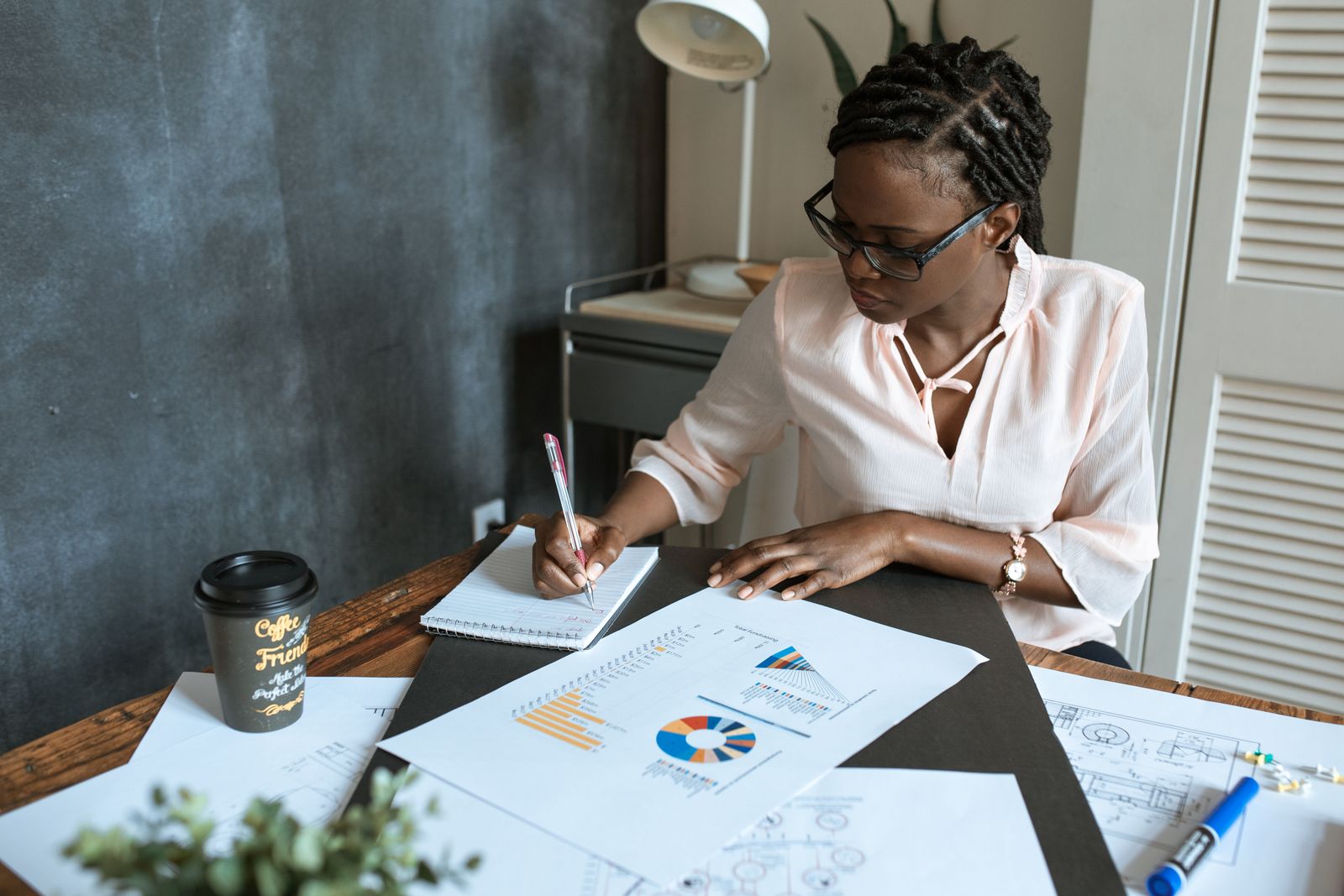 A person taking notes beside printed financial charts