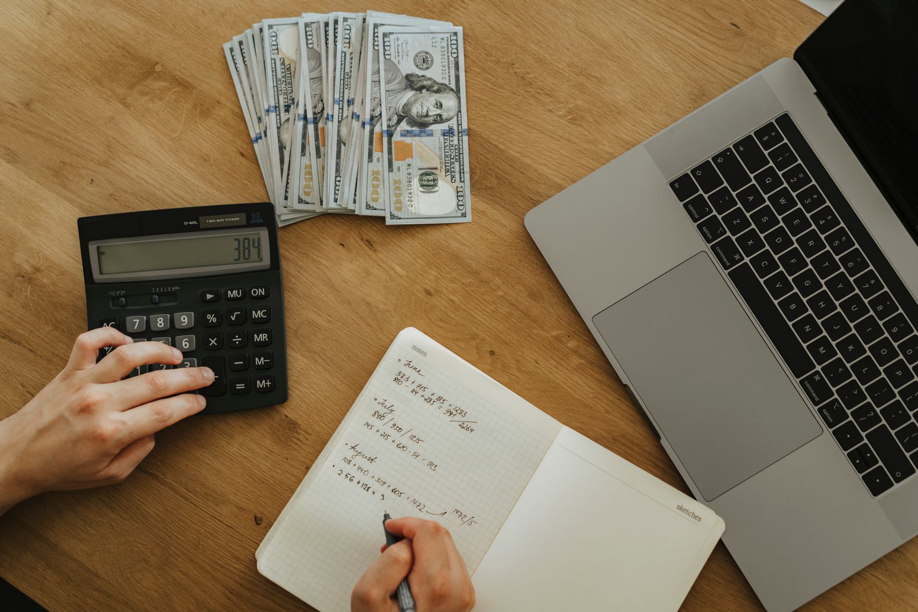 A person reviewing financial notes with a calculator at a desk